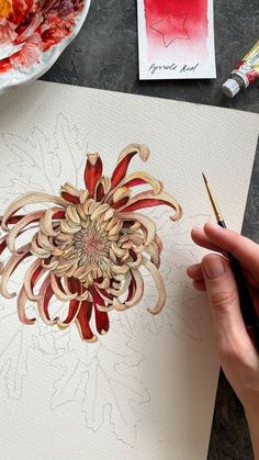 someone is drawing something with colored pencils and watercolors on paper that looks like a flower