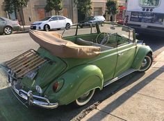 an old green car is parked on the side of the road