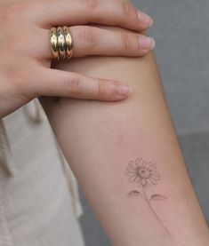 a woman's arm with a small flower tattoo on the left side of her arm