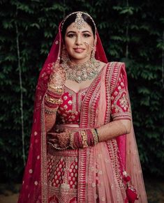 a woman in a red and gold bridal outfit with her hands on her hip