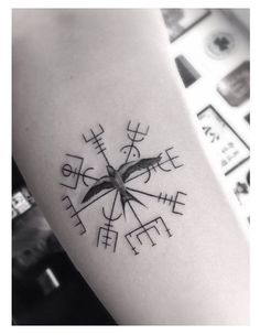 a black and white photo of a compass tattoo on the left inner arm, with chinese characters written in cursive writing