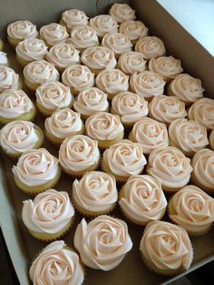 a box filled with lots of cupcakes covered in pink frosting sitting on top of a table