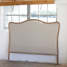 a white headboard sitting next to a window in a room with exposed wood beams