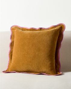 two brown and pink pillows sitting on top of a white couch next to each other