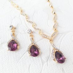 "Custom color necklace and drop earring set with your choice of premium crystal center stone colors.  This elegant and sparkly jewelry set features pave set clear diamante crystals, finished with 14mm teardrop crystal center stones.  The metal is nickel-free with your choice of gold, silver, or rose gold plating.   The necklace length is adjustable from 15\"-22\" long with a 1\" center drop.   The earrings are 1.5\" inches long and can be finished as pierced or as clipon with hinged backs that h Purple Crystal Jewelry Sets For Wedding, Elegant Purple Bridal Necklace For Wedding, Purple Crystal Jewelry Sets For Formal Occasions, Formal Purple Crystal Jewelry Sets, Elegant Purple Jewelry Sets For Wedding, Elegant Purple Jewelry Set With Matching Earrings, Elegant Purple Jewelry Sets For Formal Occasions, Purple Rhinestones Jewelry For Anniversary, Purple Rhinestone Jewelry For Anniversary