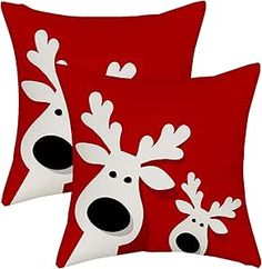 two red pillows with white and black reindeers on them, one is facing the camera