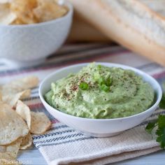 a white bowl filled with guacamole next to tortilla chips