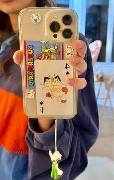 a person holding up a cell phone case with stickers on it