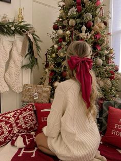 a woman sitting in front of a christmas tree