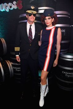 a man and woman standing next to each other in front of barrels with wine on them