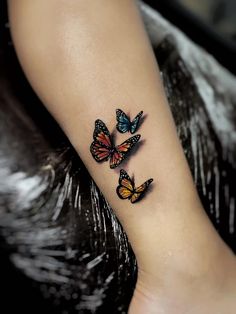 three butterflies tattoo on the left ankle and right leg, with one butterfly flying in the air