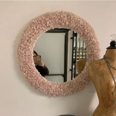 a mannequin is standing in front of a round mirror with beads on it