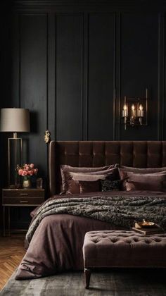 a bedroom with black walls and a bed in the middle is lit by two lamps