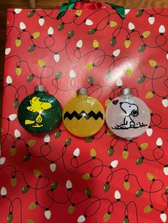 three christmas ornaments sitting on top of a red wrapping paper