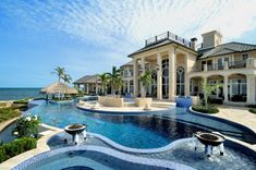 an outdoor swimming pool surrounded by palm trees and water features a gazebo with thatched umbrellas