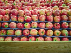 many red apples are stacked on top of each other in bins at the grocery store