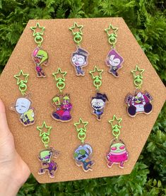 a person holding up a bunch of cartoon magnets on a piece of cork board