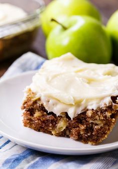 a piece of cake sitting on top of a white plate next to some green apples