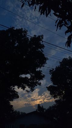 the sun is setting behind some trees