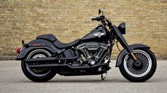 a black motorcycle parked in front of a brick wall