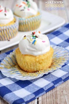 two cupcakes with white frosting and sprinkles on a plate