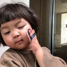 a little boy holding a cell phone to his ear