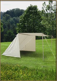 a tent set up in the middle of a grassy field with trees in the background