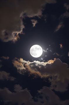 the full moon is seen through some clouds