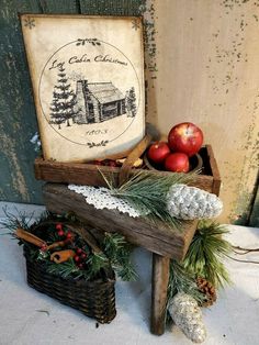 an old fashioned wooden box with apples and pine cones in it next to a sign that says cabin christmas