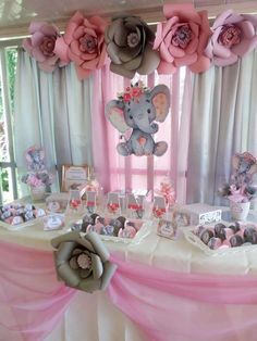 an elephant themed birthday party with pink and gray decorations on the table, flowers hanging from the ceiling