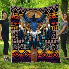 two women standing next to a blanket with an eagle on it