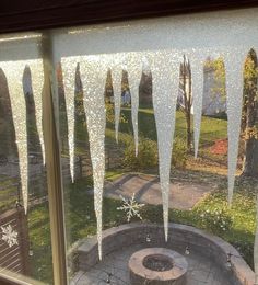 icicles are hanging from the window in front of an outdoor fire pit and walkway