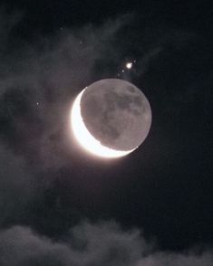 the moon is shining brightly in the dark night sky with clouds around it and stars