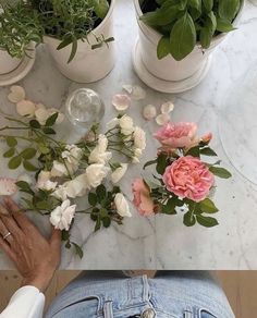 a person sitting at a table with flowers and plants in their lap tops, looking down on them