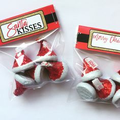 two small red and white christmas hats in plastic bags with the label santa kisses on them