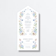 the wedding stationery is displayed on a white background with blue flowers and greenery