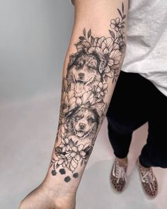 a woman's arm with flowers and two dogs on it