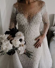 a woman in a wedding dress holding a bouquet of flowers and wearing pearls on her body