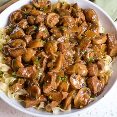 a white bowl filled with pasta covered in meat and mushroom gravy on top of a green napkin