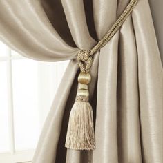 a curtain with a tassel hanging from it's side, in front of a window