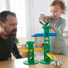 a man and child playing with toys on the table