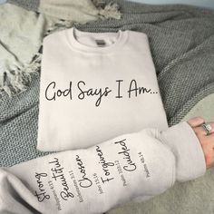 Introducing our Unisex God Says I AM sweatshirt, a cozy and stylish expression of faith. Crafted with comfort in mind, this sweatshirt features a unique design: God Says I am, printed on the front. The left sleeve displays a list of what God says we are and the bible verse associated with each quality and adjective, a powerful reminder of what we represent to God. Let this be your pick-me-up, motivational sweatshirt and a beautiful reminder to anyone who comes across it. Made from premium materi God Says I Am Shirt, Christian Clothing Ideas, Bible Verse Shirts For Women, God Says You Are, God Says I Am, Cute Christian Sweatshirts, Christian Vinyl Shirts, Christian Athletic Apparel, Christian Sweatshirt Designs