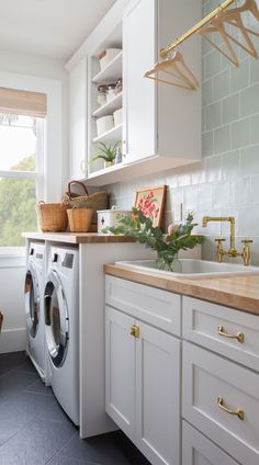 a washer and dryer in a white kitchen with wood counter tops on the counters