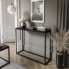 a living room with grey walls and a white console table topped with flowers in vases