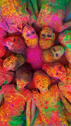 a group of children covered in colored powder are standing together and looking up at the camera