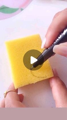 someone is using a sponge to make a small piece of yellow paper with a black marker