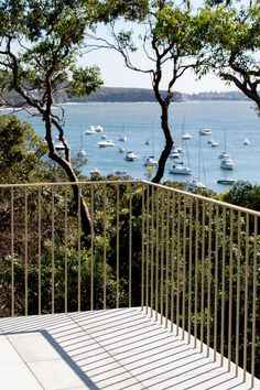 a balcony overlooking the ocean with boats in the water and trees growing on the other side