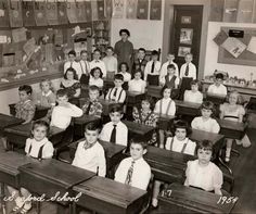 an old black and white photo of school children in their desks at the end of class