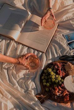 an open book and some wine on a bed