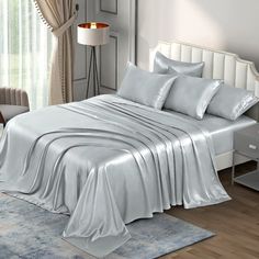 a white bed with silver sheets and pillows